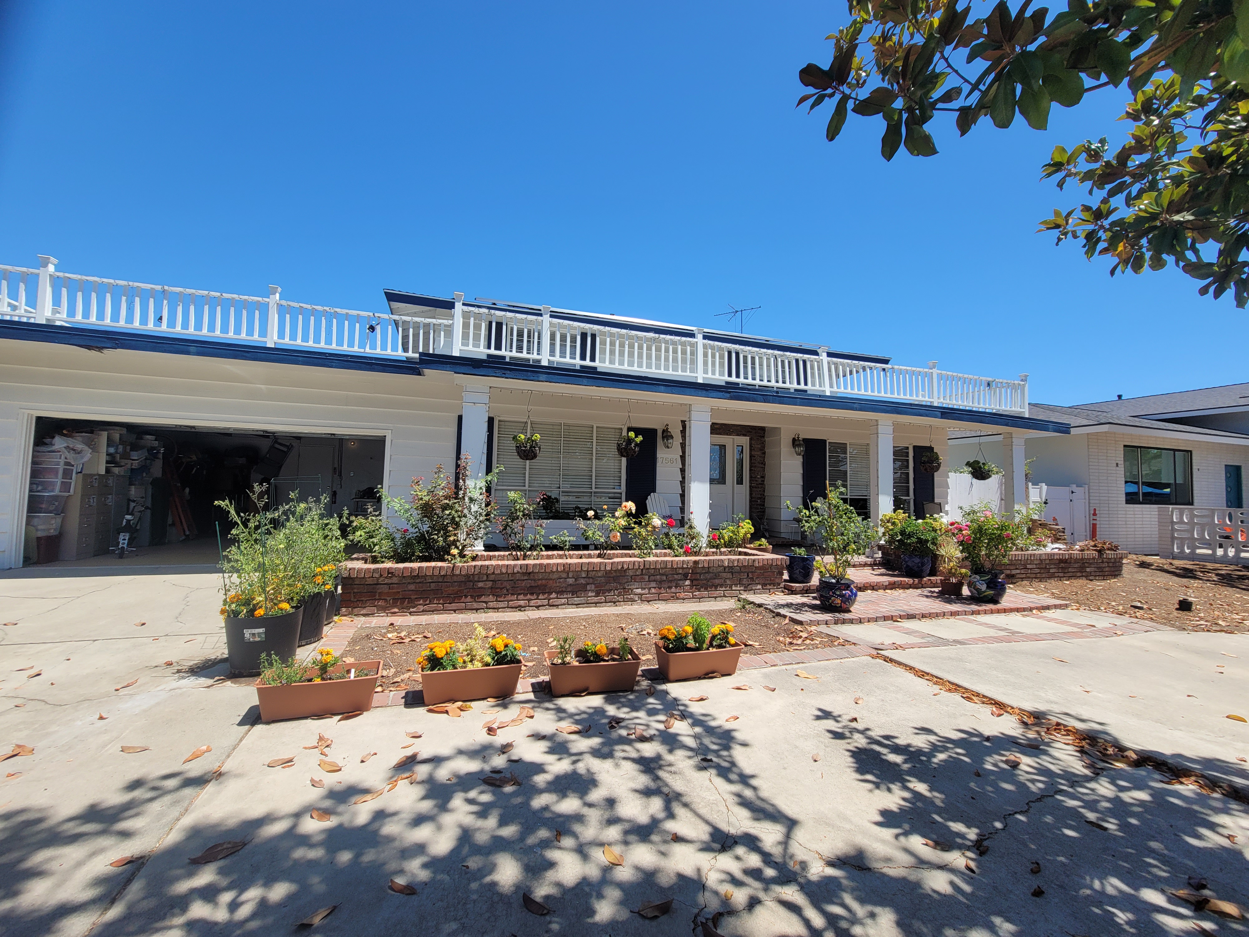 Before view of the home exterior with white-framed windows and a long upper porch railing.
